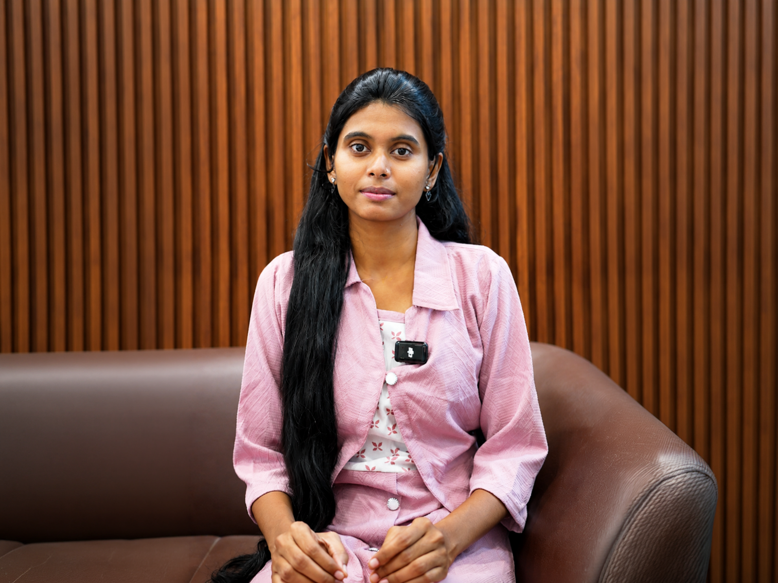 Velora learner speaking in front of a warm wood-panel backdrop